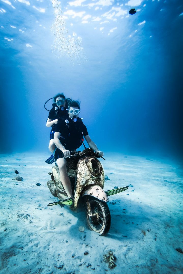 Zwei Taucher auf einem Moped unter Wasser